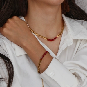 Détail du collier et bracelet en chaîne cubaine dorée avec pendentifs en zircon rouges