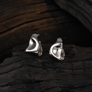 Modern irregular geometric liquid silver stud earrings on a dark textured background