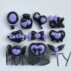 Flat lay of 9 black and purple resin charms with wing, heart, and balloon designs