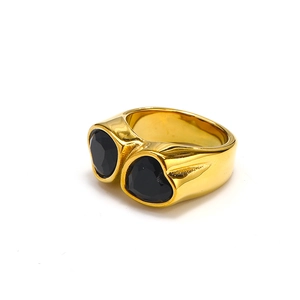 Macro detail of wide gold band ring featuring double black heart-shaped gemstones