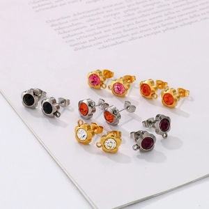 Floral stainless steel earrings with colorful rhinestones and hanging loops on a book