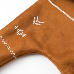 Close-up of white geometric embroidery on brown faux suede fabric of the winter jacket