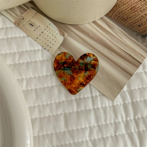 Close-up of heart-shaped acetate hair clip with tortoise shell pattern on quilted fabric