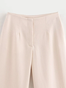 Detail shot of the cream-colored trousers showing high-quality textured fabric and stitching