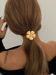 Close-up of golden metal flower ponytail holder on blonde hair from a back view