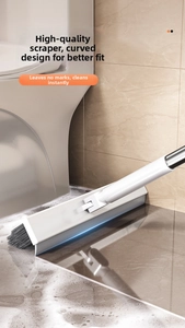 Detail view of the curved rubber squeegee and dense bristles cleaning a wet tiled floor
