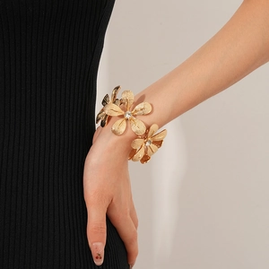 Detail eines Gold-Blumenarmbands mit funkelnden Strasssteinen am Handgelenk des Models