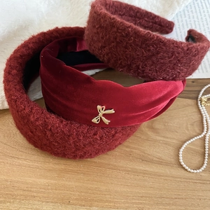 Detail of red plush and velvet headbands with golden bow accent on a wooden surface