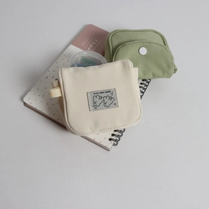 Close-up of cream and light green canvas storage bags with white snap buttons