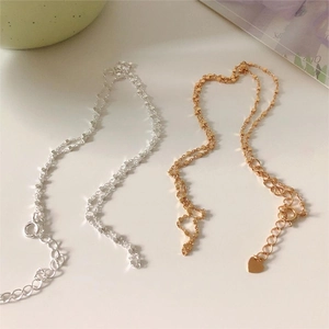 Detail of double-layer beaded chain necklaces in gold and silver with heart charm