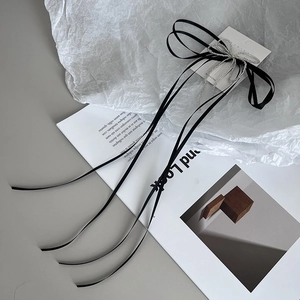 Elegant black ribbon hair clip with silver bead bow and pearl accent on white paper