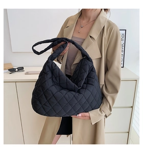 Detail of black quilted puffer tote bag with diamond stitching and soft nylon texture