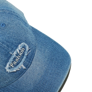 Detail of blue denim baseball cap featuring frayed patch with fashion embroidery