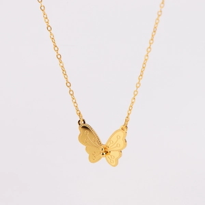 Détail du pendentif papillon doré avec textures fines sur une chaîne à maillons O