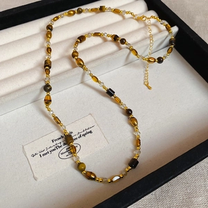 Close-up of 18K gold-plated beads and tiger eye stone necklace in a velvet jewelry box