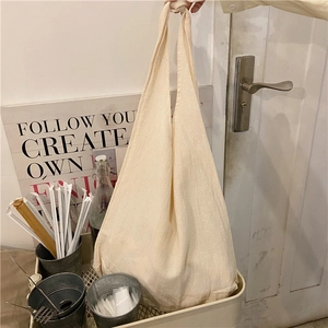 Close-up of cream canvas tote bag showing the textured fabric and knotted handle detail