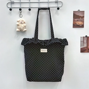 Detailed view of polka dot canvas tote with ruffled edge and lettered fabric label