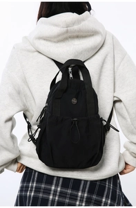 Rear view of model wearing a compact black lightweight nylon backpack for commuting