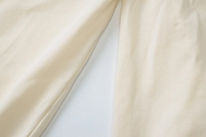Close-up of soft cream white knitted fabric texture showing fine weave details