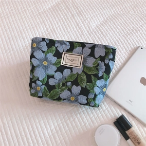 Floral jacquard canvas cosmetic bag shown with makeup and tablet in a flat lay setup