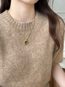 Detail of tiger eye stone pendant necklace on model with golden vintage texture