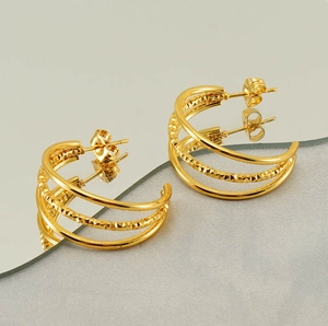 Macro shot of gold layered C-shaped earrings with polished finish and textured center