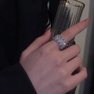 Close-up of wide silver ring with pavé-set zircons on hand holding a glass