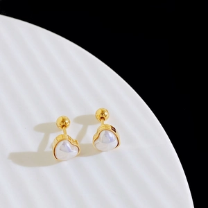 Detailed close-up of gold heart-shaped stud earrings with iridescent pearl inlay on a white tray