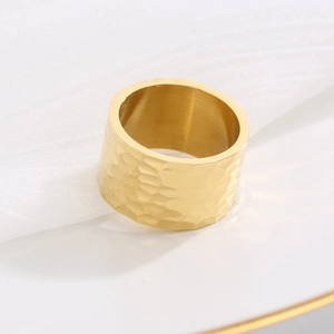 Detailopname van een brede 18K vergulde ring met gehamerde textuur en gouden glans