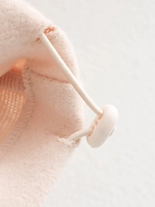 Detailed macro view of pink fleece jacket fabric with white elastic drawstring and toggle