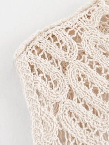 Gros plan sur le tricot beige montrant la texture ajourée complexe et les détails soignés