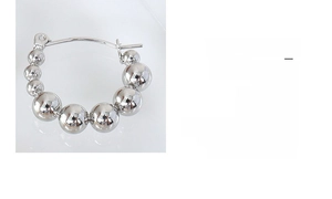 Macro detail of polished silver bead earrings showing gradient spherical steel design