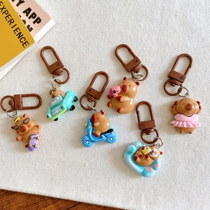Flat lay of six cute capybara keychains in various poses on a textured fabric