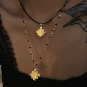Detail of 18k gold plated cross pendant necklace on black leather cord and beaded chain