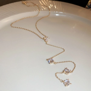 Détail d'un collier en Y doré avec zircons en goutte sur une assiette en céramique