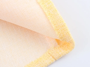Dettaglio ravvicinato del tessuto tweed giallo chiaro con trama e bordo rinforzato