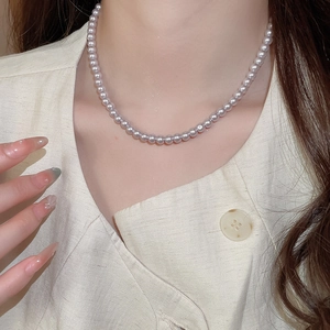 Macro detail of high-luster mauve pearl necklace worn on model for elegant styling