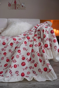 Detailed view of beige Christmas blanket with festive red prints and ruffle edge