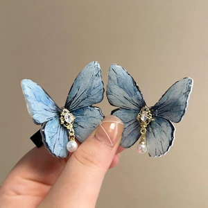 Macro shot of blue ink-textured butterfly hair clips with sparkling rhinestones and pearls