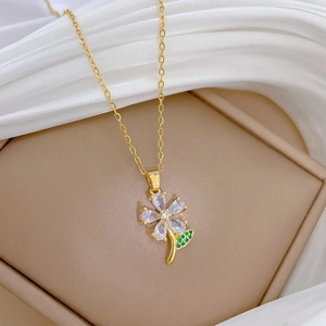 Macro shot of gold clover pendant necklace featuring green and clear zircon stones