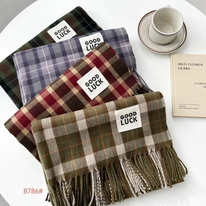 Close-up of folded thick plaid cashmere scarves with fringe and Good Luck label