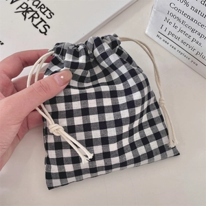 Close-up of black and white gingham drawstring pouch with cotton rope closure on white desk