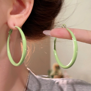 Detail of light green enamel hoop earrings showing texture and size on a model