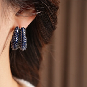 Close-up of vintage wide hoop earrings with micro-paved blue zircons on model ear