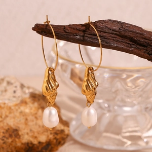 Detail of 18K gold plated conch and freshwater pearl earrings on vintage wood
