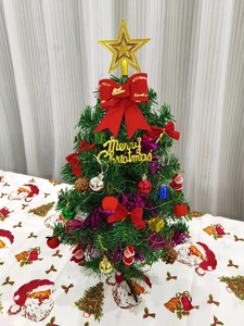 Close-up of a 30cm mini Christmas tree decorated with red bows and golden star topper