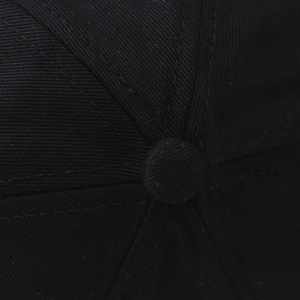 Close-up of the squatchee and sewing craftsmanship on the crown of a black cotton baseball cap