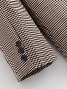 Vue macro de la manche du blazer pied-de-poule avec trois boutons noirs et texture laine