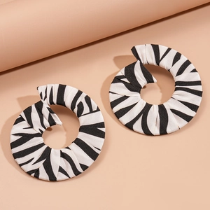 Détail du tissu à motif zèbre sur des créoles géométriques en spirale avec texture coton