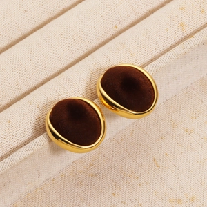 Detail of oval earrings featuring golden metal edges and dark brown flocking texture